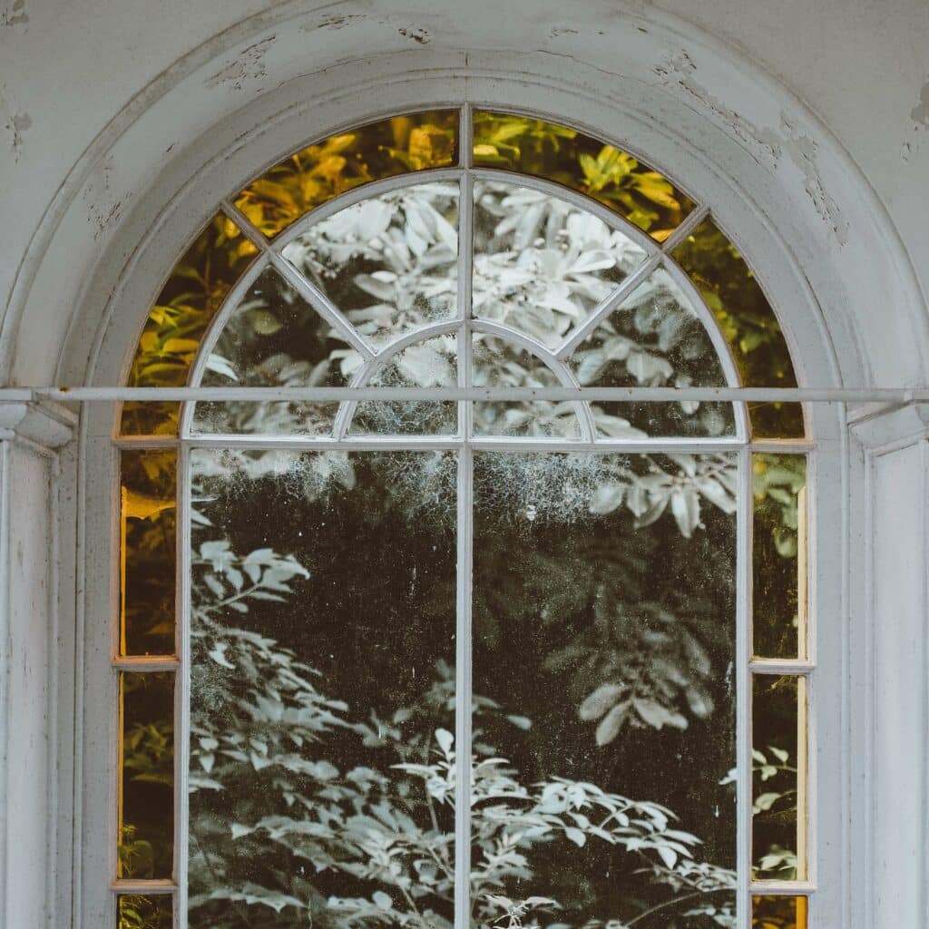 Fenster mit weißem Rundbogen mit Blick ins Grüne